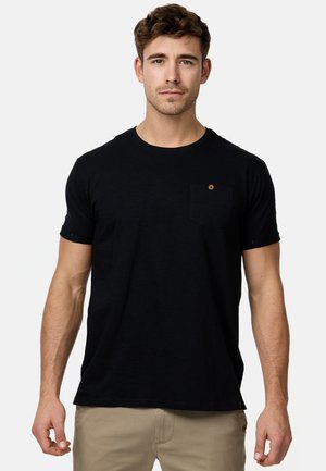 Camiseta negra de manga corta con cuello redondo, un bolsillo en el lado izquierdo del pecho y un pequeño botón decorativo circular. Textura de algodón suave.