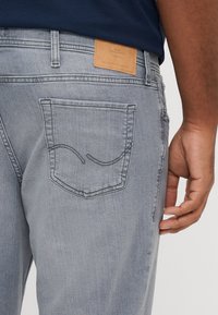 Γκρίζα τζιν παντελόνια από τζιν ύφασμα με πίσω τσέπη που διαθέτει κυρτό σχέδιο ραφής. Δερμάτινη ετικέτα στη μέση φανερώνει το κε�ίμενο "JEANS INTELLIGENCE".