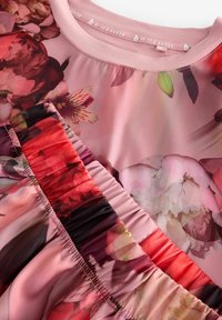 Kvetinový set blúzky a sukne v ružových odtieňoch; vyznačuje sa živými kvetinovými vzormi, hladkou textúrou a detailom nariasenej pásovky.