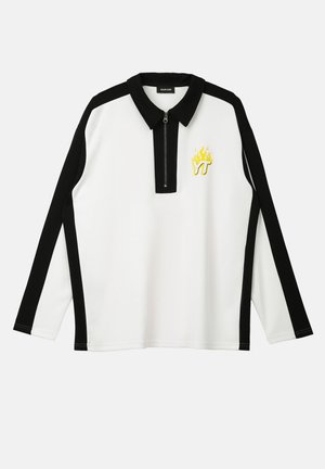 Hvit og svart langermet polo skjorte med glidelås krage, med en gul flamme logo og kontrasterende svarte striper på ermene.