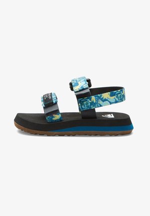 Sort sandal med blå og gule mønstrede justerbare stropper, tyk sål med blå stribe og brun tekstureret ydersål.