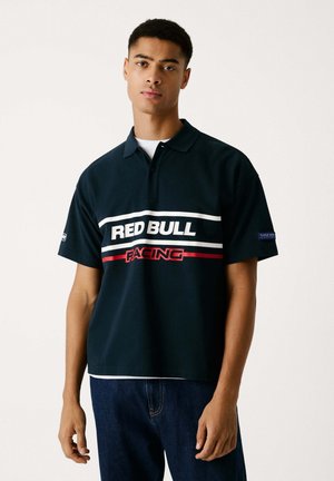 Sötét navy kék póló, rövid ujjakkal, fehér és piros „RED BULL RACING” felirattal a mellkasán. Pamut keverék anyag.