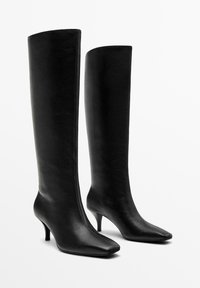 Stivali neri al ginocchio in pelle liscia, con punta affusolata, tacco sottile e design elegante e aderente.