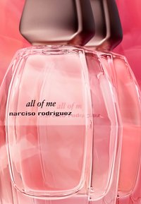 Bouteilles de parfum en verre transparent avec une teinte rose, présentant un design épuré et un capuchon en bronze. Le texte indique "tout de moi" et "narciso rodriguez."