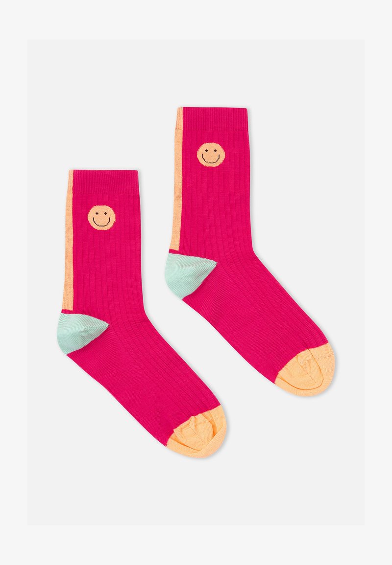 Calcetines de caña media rosa con acentos naranjas y talones verde menta, con un diseño de cara sonriente. Vista desde arriba sobre un fondo blanco.