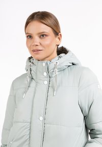 Giacca puffer verde chiaro con cappuccio, dotata di bottoni automatici, cordini elastici e tessuto trapuntato. Materiale liscio e resistente all'acqua.