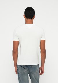 Λευκό κοντομάνικο μπλουζάκι με στρογγυλή λαιμόκοψη, κατασκευασμένο από απαλό ύφασμα. Διαθέτει λεία υφή και απλό, καθαρό σχέδιο.