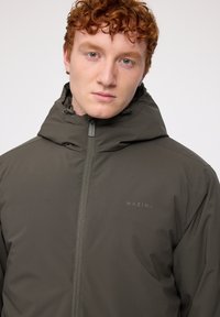 Olive green hooded jacket made of smooth, durable fabric featuring a front zipper and a small logo on the left chest.