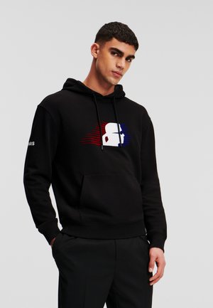 Schwarzer Hoodie mit einer Fronttasche, der ein grafisches Design in Rot, Weiß und Blau zeigt. Er hat Kordeln und gerippte Bündchen.