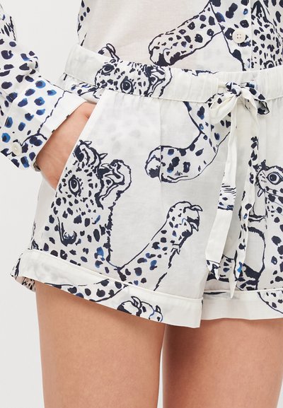 Weiße Shorts mit einem blauen und schwarzen Leopardenmuster, ausgestattet mit einem elastischen Bund, zwei vorderen Taschen und einem gebundenen Schleifendetail an der Taille.