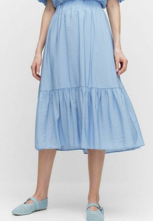 Himmelblaues, gestuftes Midikleid aus leichtem Stoff, mit einem gerafften Bund und fließendem Design; kombiniert mit hellblauen, perforierten Ballerinas.