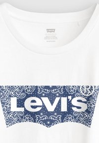 Λευκό μπλουζάκι με μεγάλο μπλε και άσπρο σχέδιο paisley στο λογότυπο και τη λέξη "Levi's" σε έντονα λευκά γράμματα στο κέντρο.