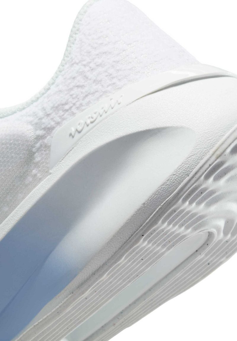 Scarpa sportiva bianca con una parte superiore testurizzata, un tallone in materiale sintetico liscio e una suola in gomma testurizzata con motivi circolari antiscivolo.