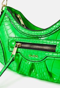 Borsa a tracolla verde in finta pelle di coccodrillo con zip dorata, dettagli plissettati e un'etichetta frontale con brand. Presenta un rivestimento interno nero.