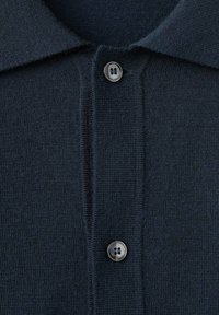 Granatowa dzianinowa koszulka polo z klasycznym kołnierzykiem, z dwukolorową plisą na guziki i gładką teksturą, podkreślająca proste detale designu.