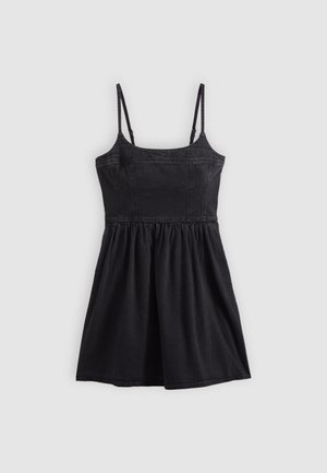 Robe noire sans manches avec bretelles fines réglables, corsage ajusté et jupe froncée, étalée à plat sur un fond gris clair.