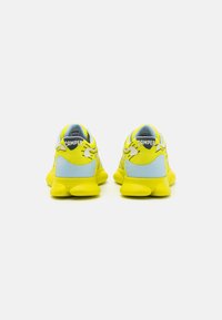 Sneakers featuring a vibrant yellow upper with blue accents, textured material, and a chunky sole design. CAMPR branding visible.