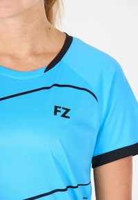 Ljusblå träningsskjorta med svart rundhals, försedd med svarta ränder och en "FZ"-logga på framsidan, tillverkad av mjukt och andningsbart material.