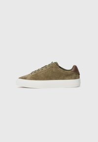 Olive green suede sneakers feature a white rubber sole, dark brown leather heel accents, and matching green laces with a rounded toe design.