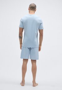 Ανοιχτό μπλε κοντομάνικο πουκάμισο και ταιριαστό σορτς, μαλακό ύφασμα, άνετη εφαρμογή, μονόχρωμο σχέδιο, χωρίς ορατά μοτίβα ή μεταλλικά στοιχεία.