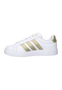 Witte sneaker met drie verticale gouden strepen, afgeronde neus, platte zool en witte veters. Glad lederen materiaal. Gouden logo op de tong.