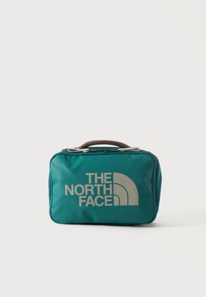 Türkisfarbene, rechteckige Kulturtasche mit Reißverschluss und Griff, mit großem weißen The North Face-Logo auf der Vorderseite.