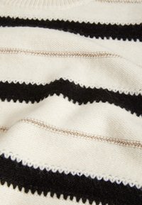 Pull en tricot avec des rayures horizontales noires, crème et beige ; texture douce avec des coutures en zigzag et de fines touches métalliques.