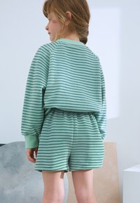 Ensemble de sweat-shirt et short rayé vert en matériau doux. Il comprend des manches longues et une taille élastique avec une coupe décontractée.