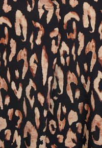 Tissu noir avec un motif léopard dans des tons de beige et de marron, avec des formes et des textures variées créant une apparence animaliste.