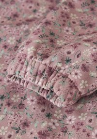 Stoff im Blumenmuster in Rosa- und Lilatönen, mit kleinen Blumen und Blättern. Der Rand ist gerafft und zeigt eine strukturierte Oberfläche.