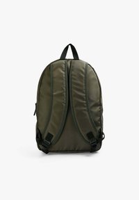Mochila verde oliva con textura acolchada, correas ajustables y costuras reforzadas. Cuenta con un asa en la parte superior y un bolsillo lateral.