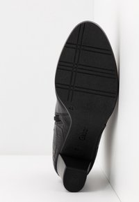 Semelle de chaussure noire avec motif croisé, taille 4½, talon carré, et nom de marque "Gabor" visible sur fond blanc.