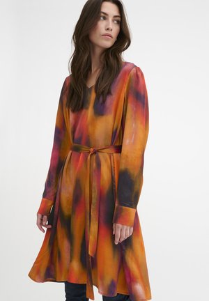 Lang, løstsiddende kjole lavet af letvægtsstof, der har et livligt orange, rødt og lilla tie-dye mønster, samt et bundet taljebælte.