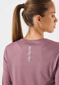 Pitkähihainen, kevyt paita mauven sävyssä, jossa on teksturoidusta kankaasta. Takana on "SWEDEMOUNT"-logo. Minimalistinen muotoilu, pyöreä pääntie.