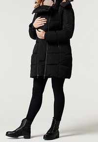 Černá péřová bunda s vysokým límcem a kožešinovým lemem, s dlouhým zipem a prošívaným designem. Nosit s černými skinny džínami a šněrovacími botami.