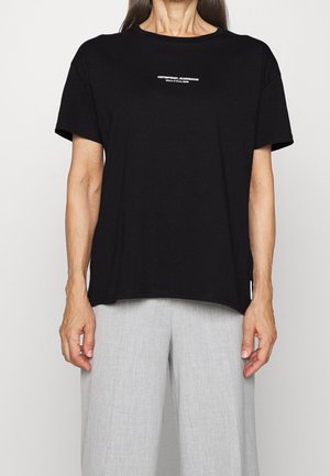 Camiseta negra de algodón con mangas cortas y cuello redondo. Texto impreso en blanco en el pecho que dice "CONTEMPORARY SCANDINIAN."