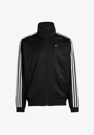 Musta vetoketjullinen takki sileästä kankaasta, jossa on korkea kaulus ja joustavat hihansuut. Takissa on valkoiset kolme raitaa hihoissa ja pieni logo.