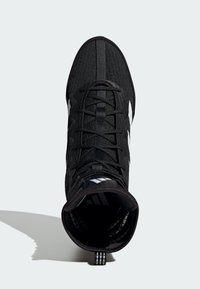 Sort atletisk sko med en struktureret overdel, der har en rund tå, snøring og hvide accentstriber på siderne.