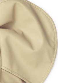 Tessuto beige con una texture liscia e opaca. Presenta pieghe morbide e un angolo arrotondato con cuciture visibili lungo il bordo.