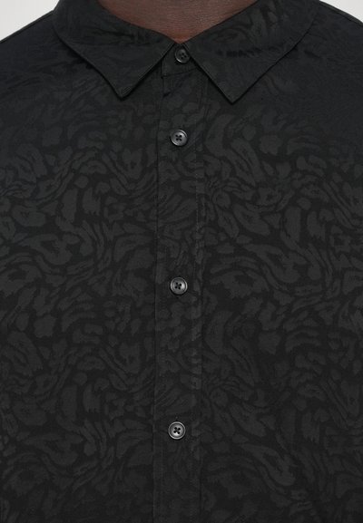 Black shirt featuring a textured pattern, soft fabric, pointed collar, and black buttons running down the front.