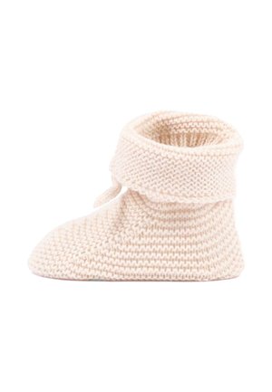 Chaussette pantoufle tricotée de couleur crème douce avec un revers plié et un détail noué, conçue pour la chaleur et le confort.