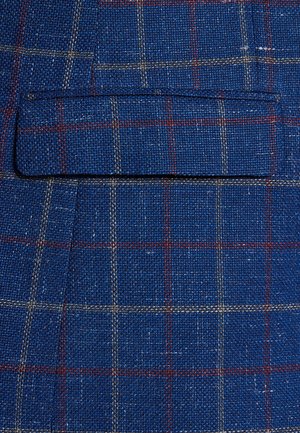 Niebieska tkanina w kratę o teksturowanym splocie, z klapą kieszeni i kontrastującymi czerwonymi i białymi liniami w wzór kratki.