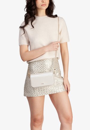 Bolso cruzado de charol crema con cadena, de forma rectangular, que presenta una textura suave y un diseño minimalista.
