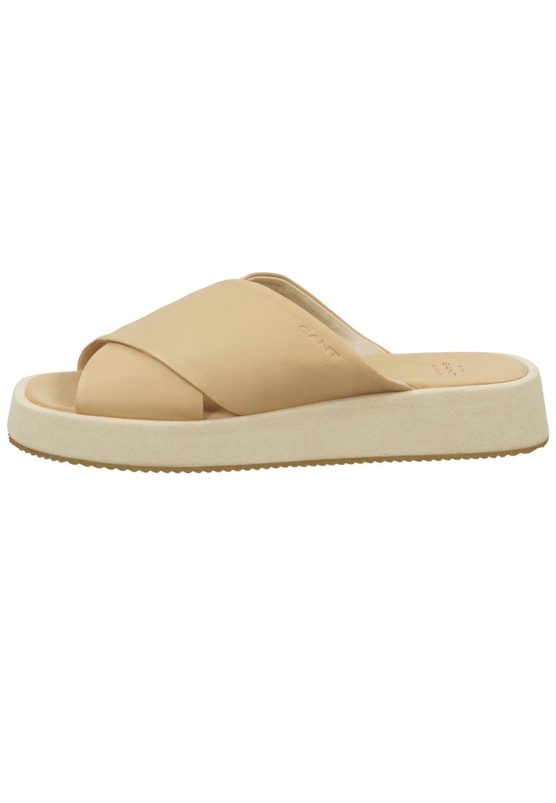 Tan leather slide sandal with cross-band design, a cushioned cream sole, and textured outsole for grip. Minimalist style with soft finish.