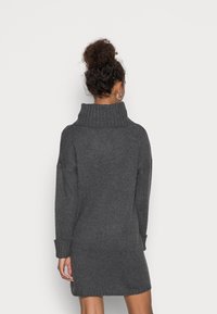 Abito lavorato a maglia grigio scuro con colletto alto, maniche lunghe e silhouette aderente. Texture a coste su tutta la superficie con dettagli ai polsini.