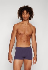 Cuecas boxer masculinas roxas feitas de um tecido liso e elástico. Apresentam um ajuste justo com uma cintura lisa e sem padrões ou detalhes visíveis.
