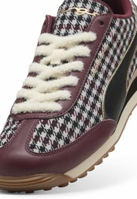 Sneaker con una toma in pelle bordeaux e tessuto a motif houndstooth, lacci crema, logo dorato e suola in gomma testurizzata.