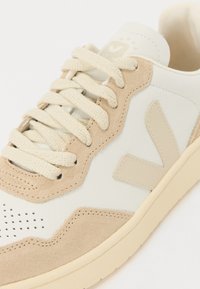 Le sneaker presentano un pannello in pelle bianca e camoscio beige, lacci rotondi beige, perforazioni sulla punta e un logo beige sulla linguetta.