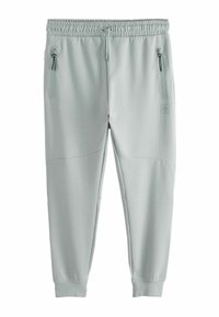 Pantaloni de trening gri deschis, cu un brâu elastic, două buzunare laterale cu fermoar și panouri din țesătură texturată pe laturi.
