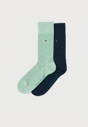 Vaaleanvihreät ja tummansiniset sukat; toinen on geometrisella kuviolla ja toinen yksivärinen. Molemmissa on vihreällä "Tommy Hilfiger" -logo.